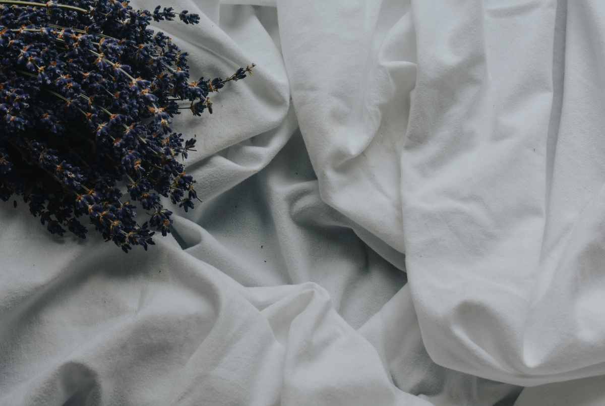 Blue bed sheets, with lavanda flowers on top